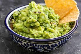 guacamole in a traditional Mexican bowl with a couple of tortilla chips